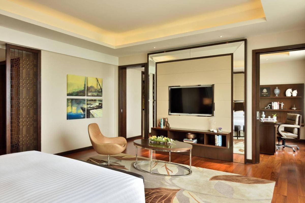 a bedroom with a bed and a table and a television at Kochi Marriott Hotel in Cochin