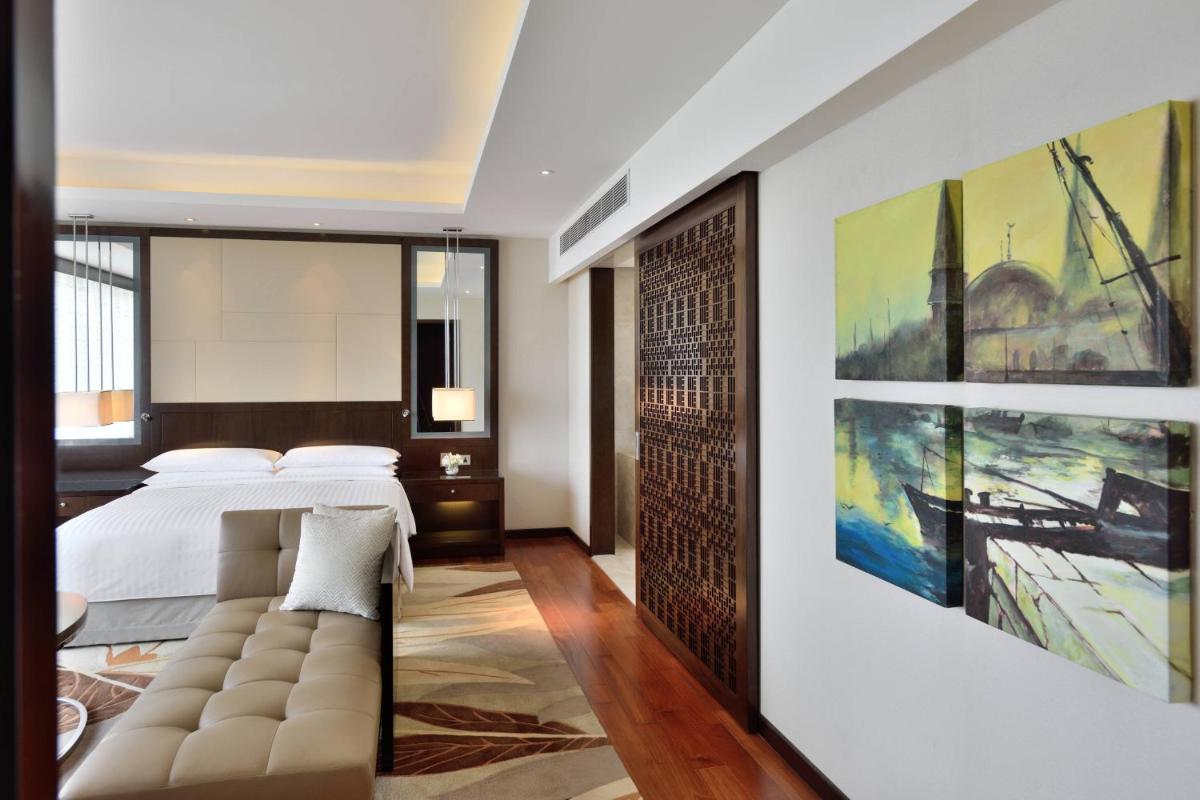 a bedroom with a bed and a large painting on the wall at Kochi Marriott Hotel in Cochin
