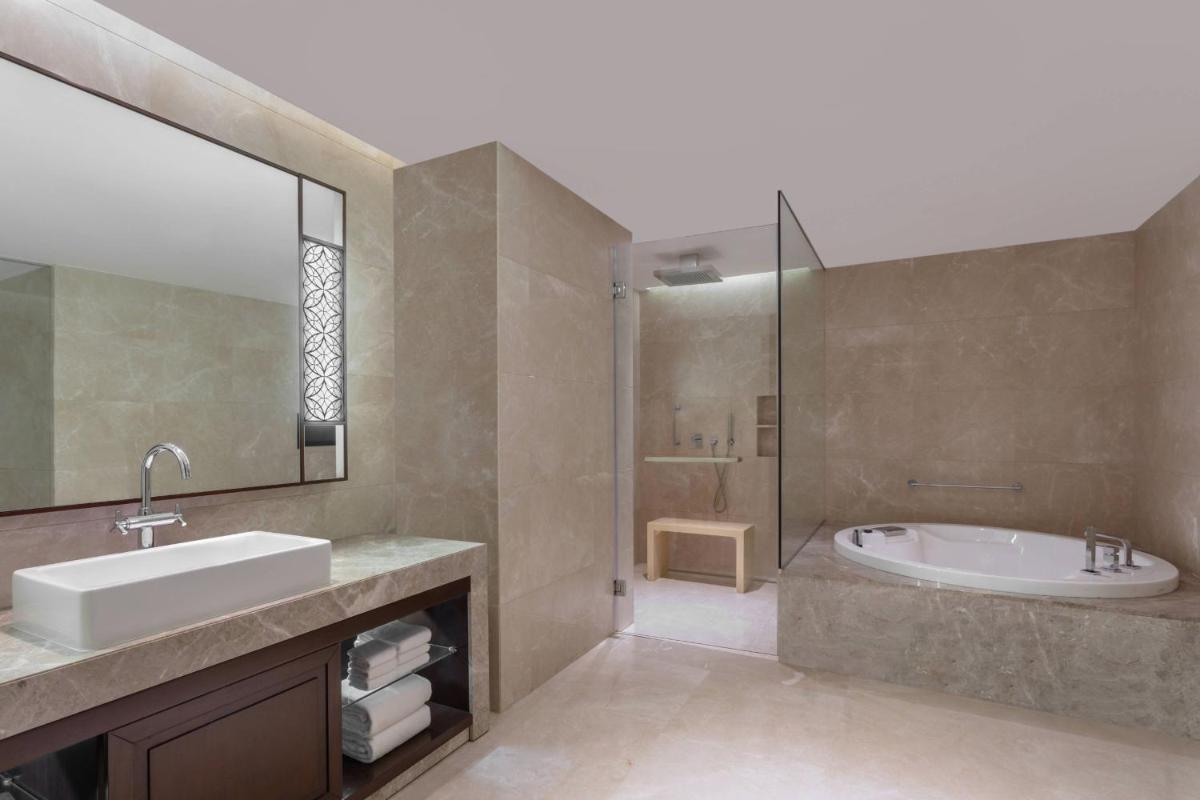 a bathroom with a sink and a tub and a mirror at Kochi Marriott Hotel in Cochin
