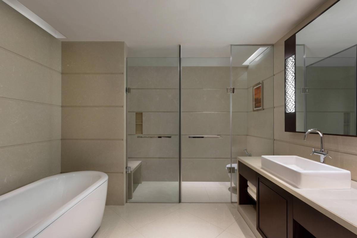 a bathroom with a tub and a sink and a mirror at Kochi Marriott Hotel in Cochin