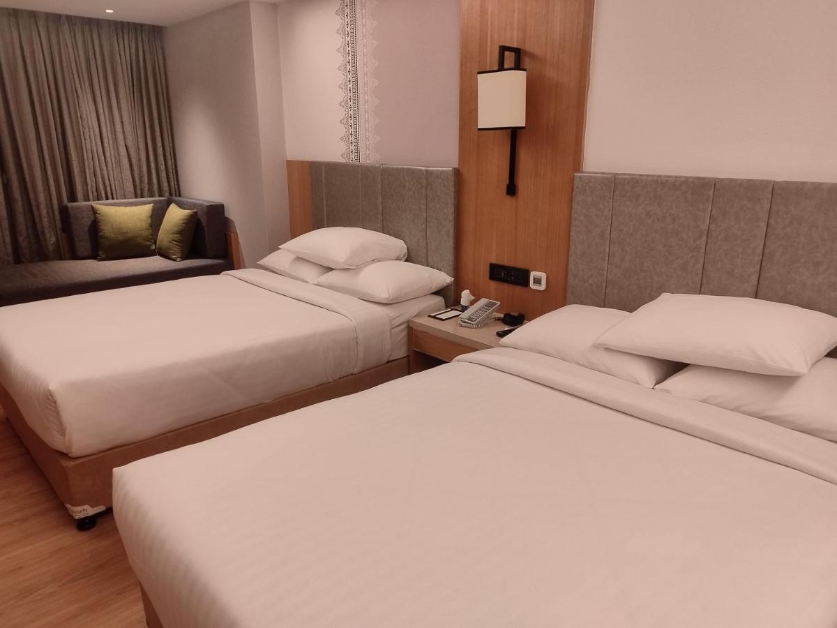 a hotel room with two beds and a telephone at Courtyard by Marriott Tiruchirappalli in Tiruchchirāppalli