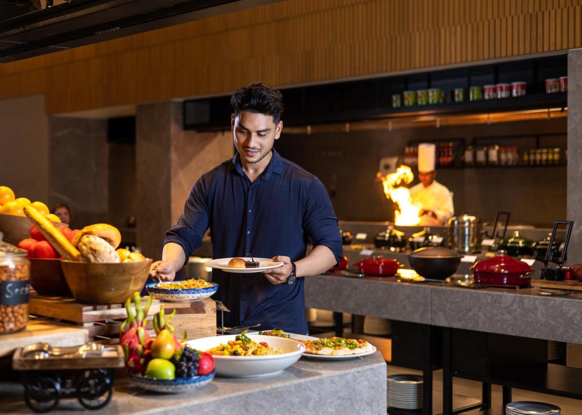 a man standing in a kitchen preparing food at Courtyard by Marriott Tiruchirappalli in Tiruchchirāppalli