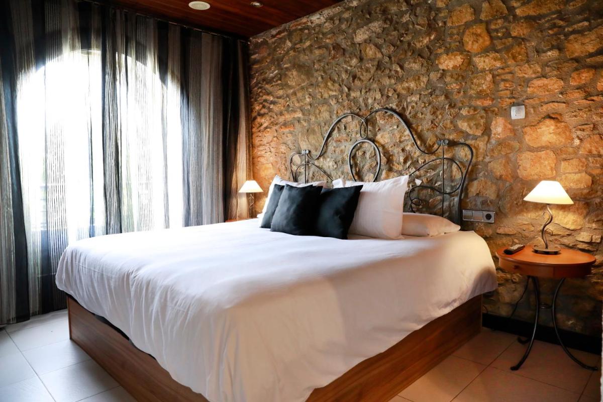 Un dormitorio con una cama grande con una pared de piedra. en La Violeta HOTEL SPA & CHILL OUT, en Castelltersol