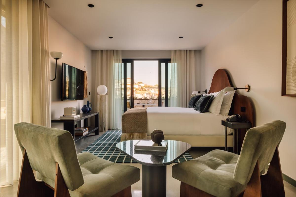 um quarto de hotel com uma cama, uma mesa e cadeiras em The Rebello Hotel & Spa - Small Luxury Hotels Of The World em Vila Nova de Gaia um quarto de hotel com uma cama, uma mesa e cadeiras em The Rebello Hotel & Spa - Small Luxury Hotels Of The World em Vila Nova de Gaia