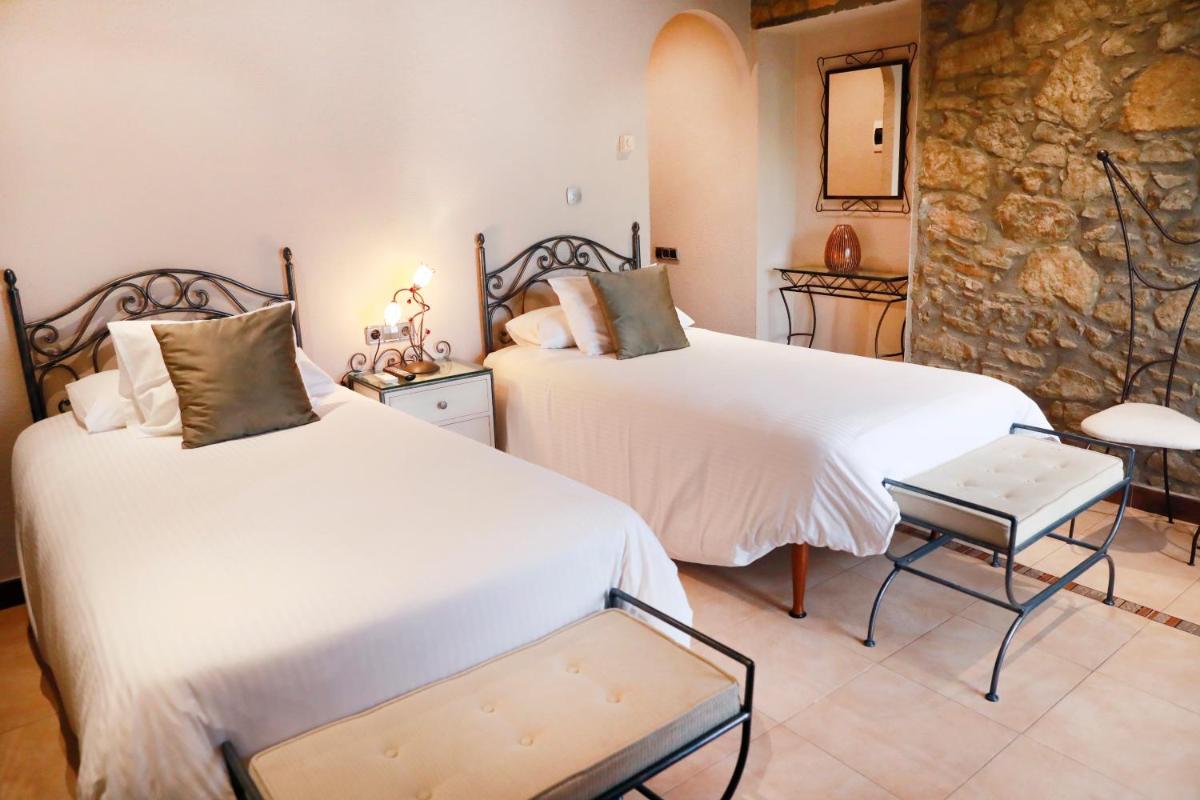Un dormitorio con dos camas y una pared de piedra. en La Violeta HOTEL SPA & CHILL OUT, en Castelltersol