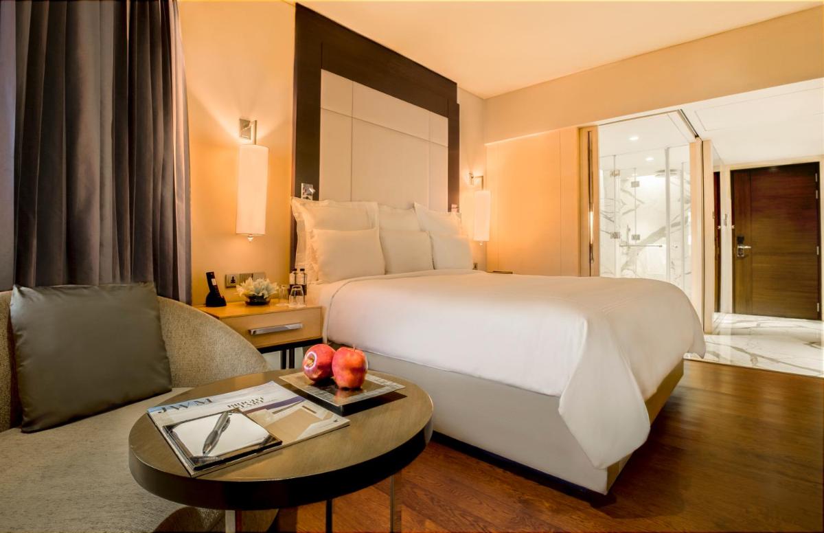a hotel room with a large bed and a table at JW Marriott Mumbai Juhu in Mumbai