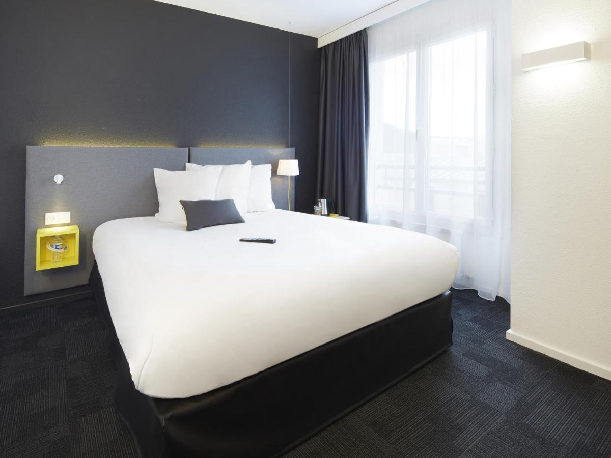 un grand lit blanc dans une chambre d'hôtel dans l'établissement Kyriad Hotel Brest, à Brest