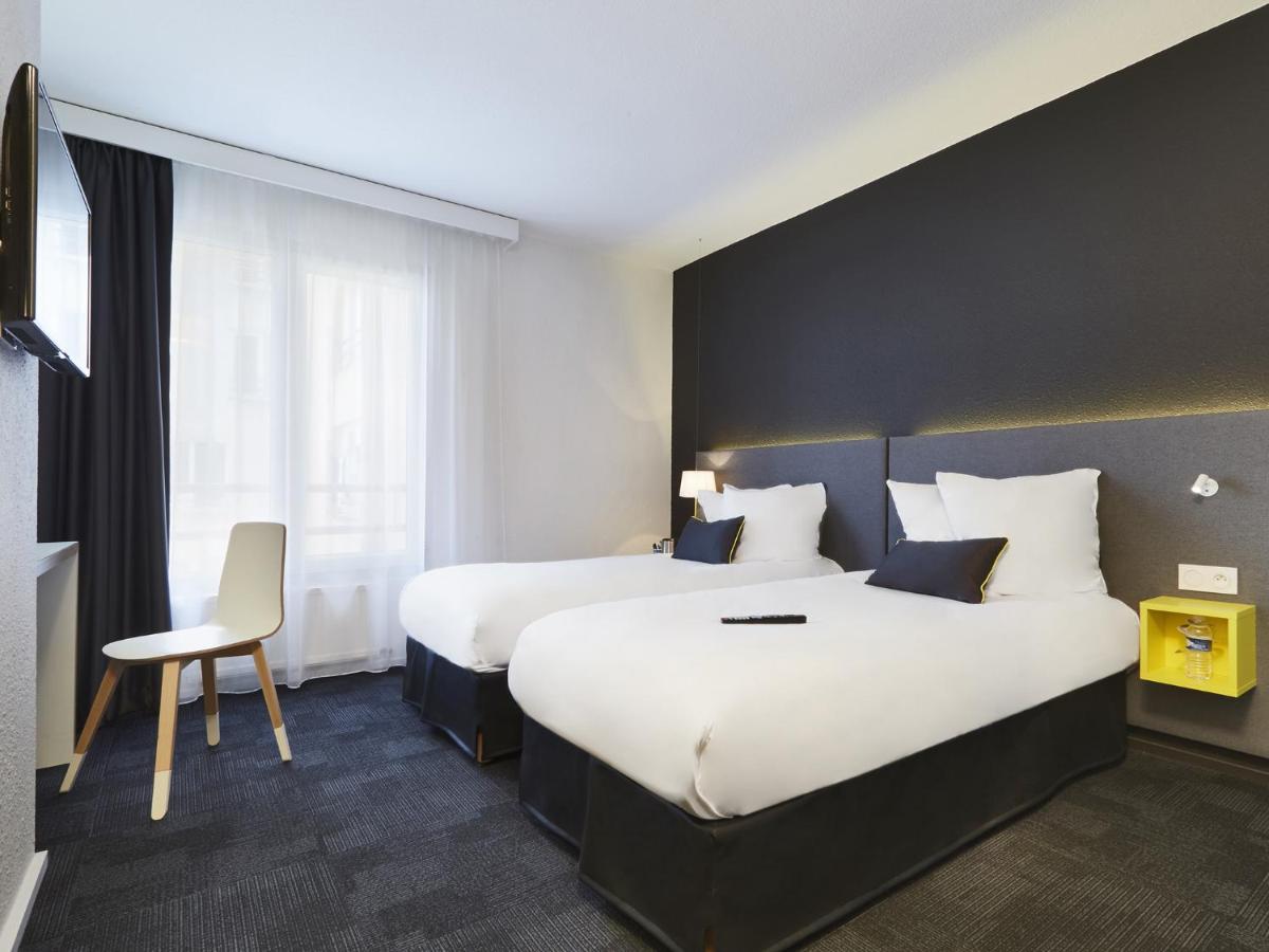 une chambre d'hôtel avec deux lits et une chaise dans l'établissement Kyriad Hotel Brest, à Brest