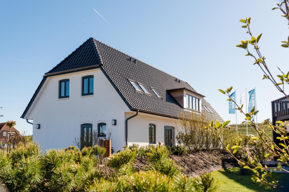 ein weißes Haus mit einem schwarzen Dach in der Unterkunft Seaside 43 in Sankt Peter-Ording