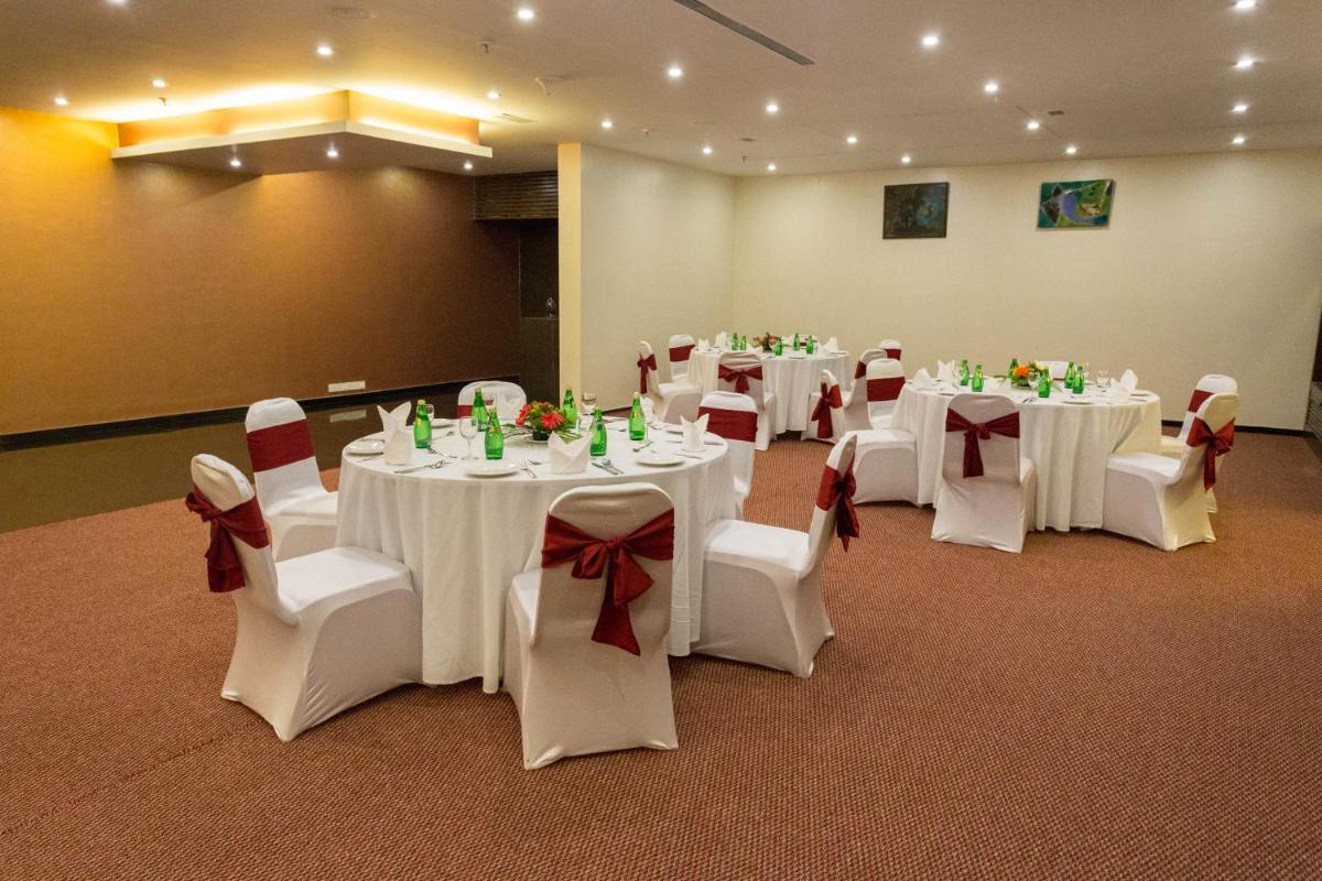 a room with tables and chairs with white tables and bows at Svenska Design Hotel in Mumbai