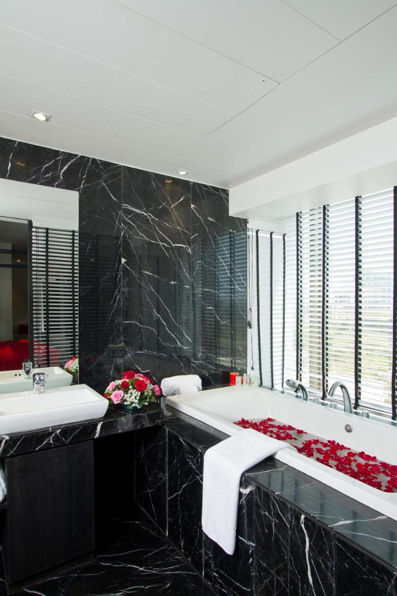 a bathroom with a large tub and a large mirror at Svenska Design Hotel in Mumbai