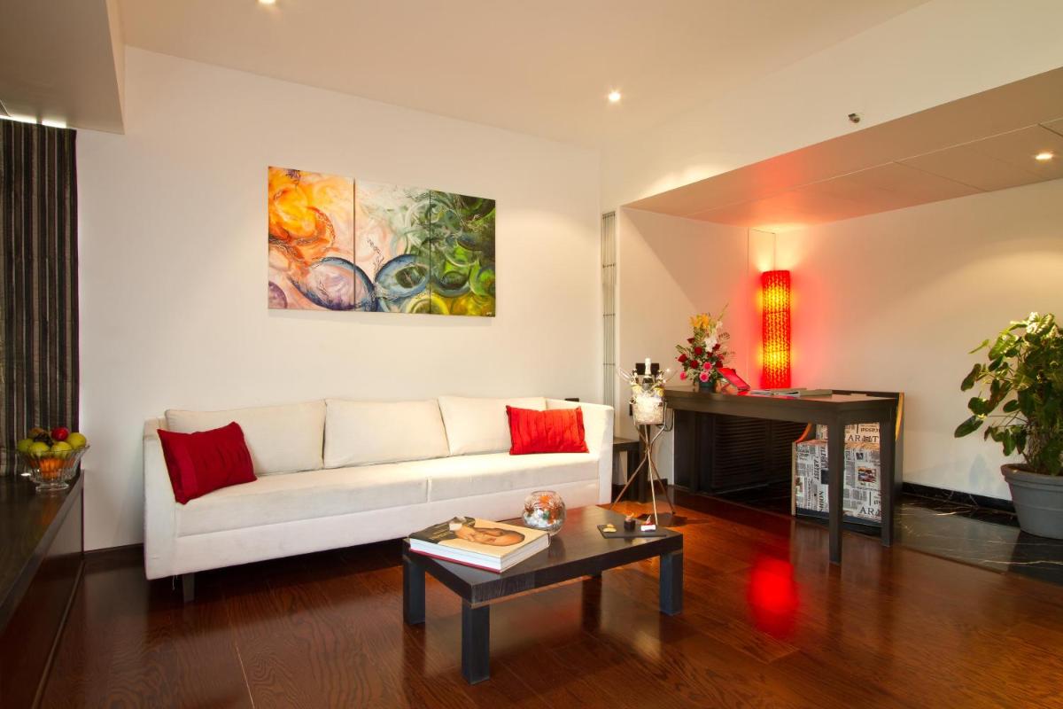 a living room with a white couch and a painting on the wall at Svenska Design Hotel in Mumbai
