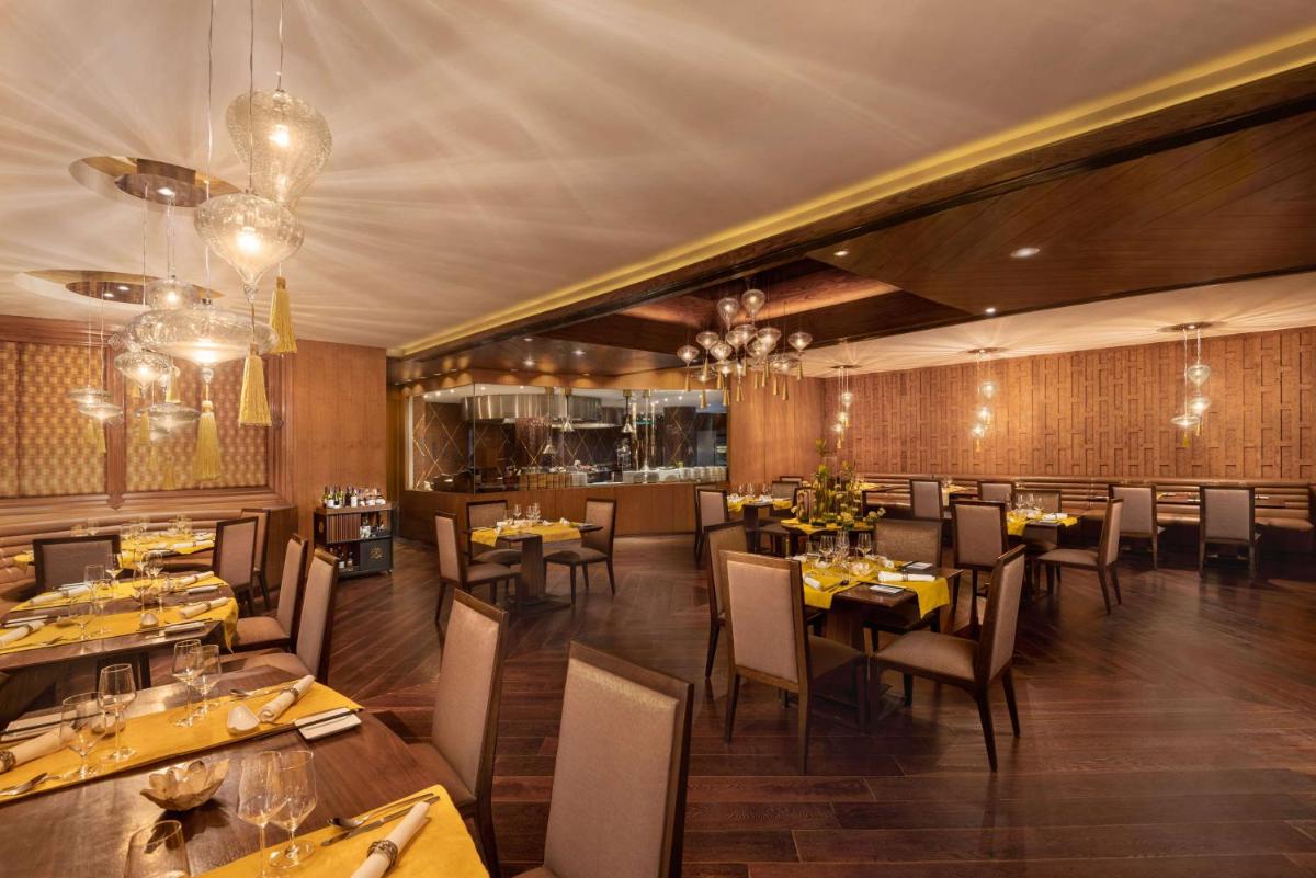 a restaurant with tables and chairs in a room at Radisson Blu Plaza Delhi Airport in New Delhi a restaurant with tables and chairs in a room at Radisson Blu Plaza Delhi Airport in New Delhi