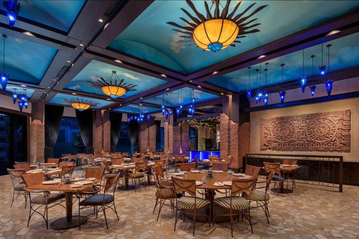 a dining room with tables and chairs and lights at Radisson Blu Plaza Delhi Airport in New Delhi a dining room with tables and chairs and lights at Radisson Blu Plaza Delhi Airport in New Delhi