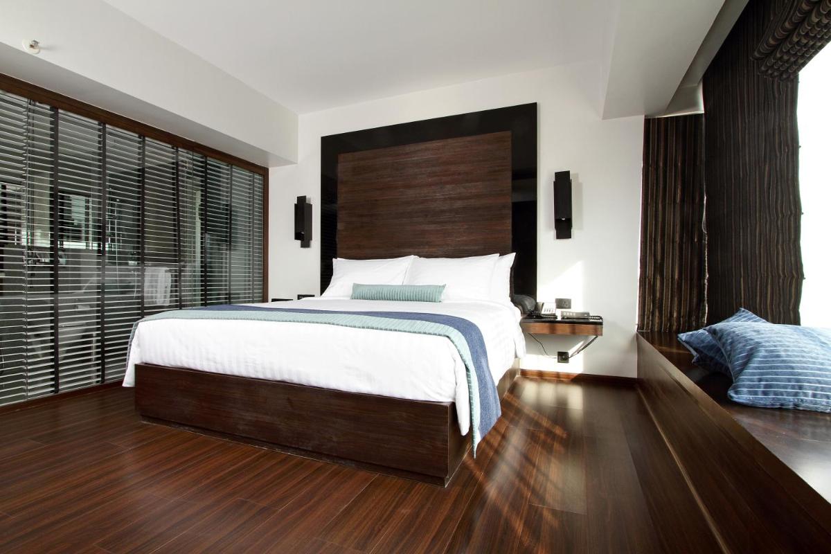 a bedroom with a large bed with a wooden headboard at Svenska Design Hotel in Mumbai a bedroom with a large bed with a wooden headboard at Svenska Design Hotel in Mumbai