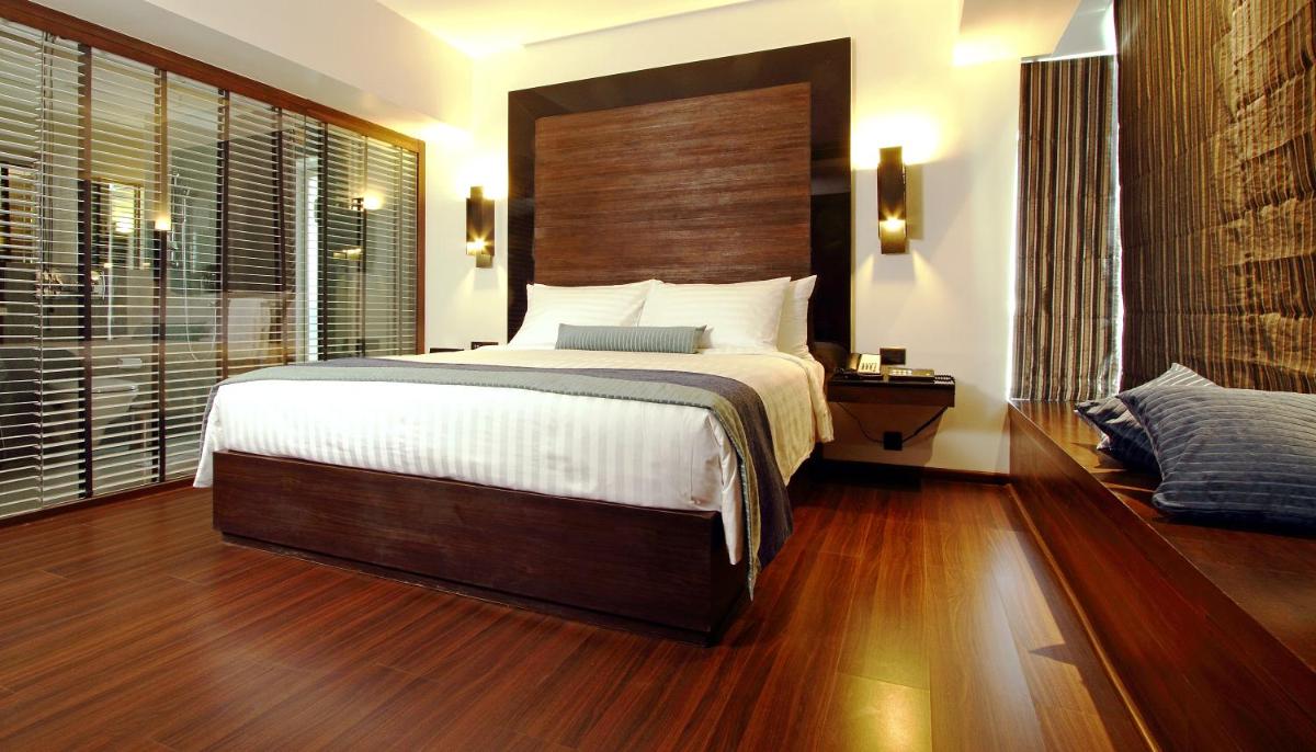 a bedroom with a large bed with a wooden headboard at Svenska Design Hotel in Mumbai