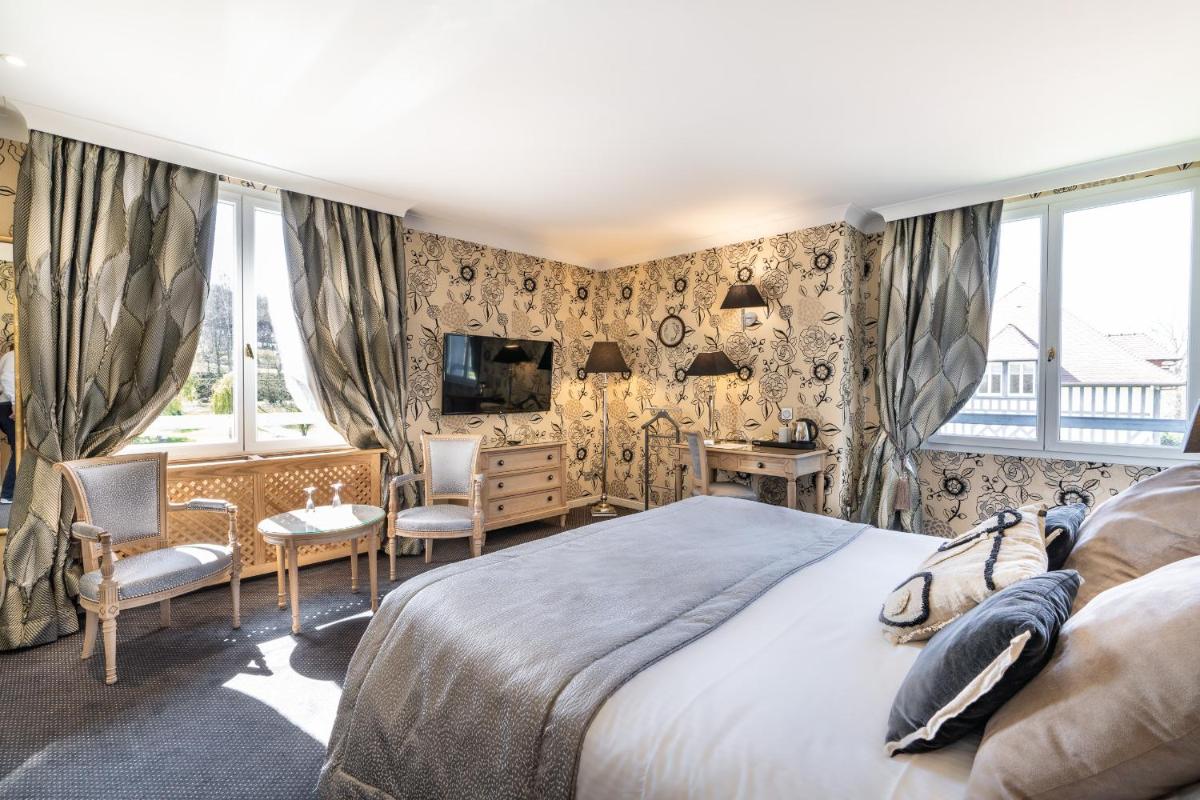 une chambre avec un grand lit et un bureau dans l'établissement Le Manoir De La Poterie & Spa, à Cricquebœuf 61 autres photos