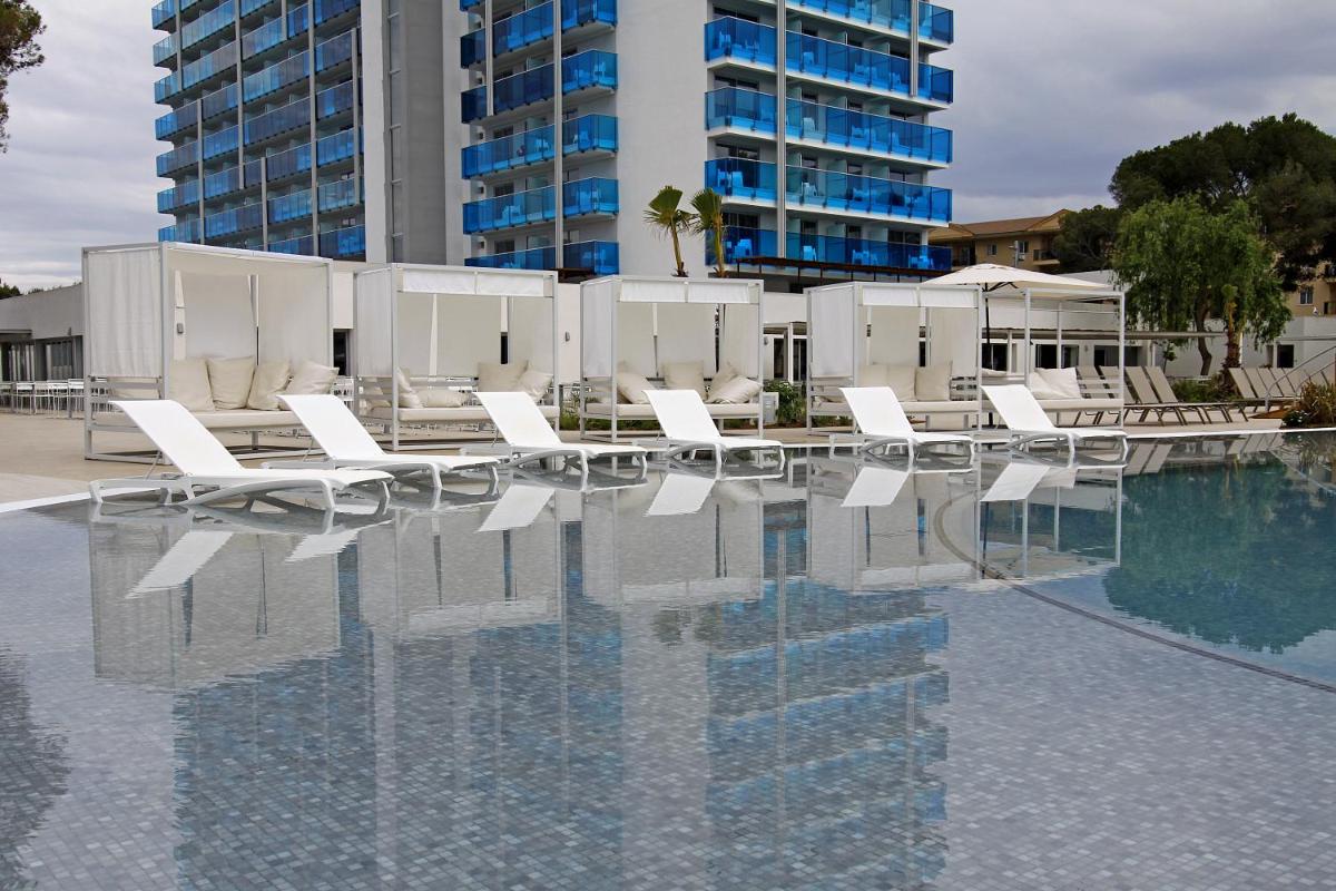 una piscina con tumbonas blancas y un edificio en BG Tonga Tower, en Can Picafort