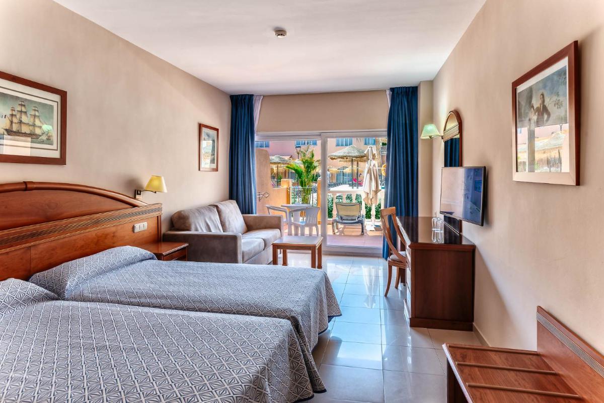 Una habitación de hotel con dos camas y una sala de estar. en Bahía Tropical, en Almuñécar