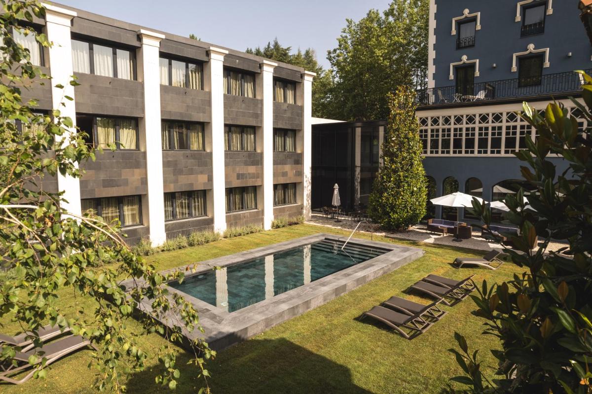 un patio con piscina frente a un edificio en Balneario Font Vella- Adults Only, en Sant Hilari Sacalm un patio con piscina frente a un edificio en Balneario Font Vella- Adults Only, en Sant Hilari Sacalm