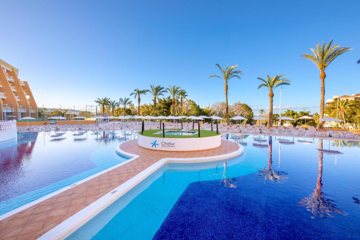 una piscina en un resort con palmeras en Chatur Playa Real Resort, en Adeje
