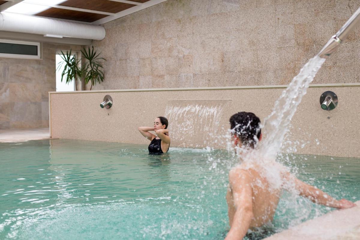 um homem e uma mulher a brincar numa fonte em Hotel Do Parque - Congress & SPA nas Termas de São Pedro do Sul