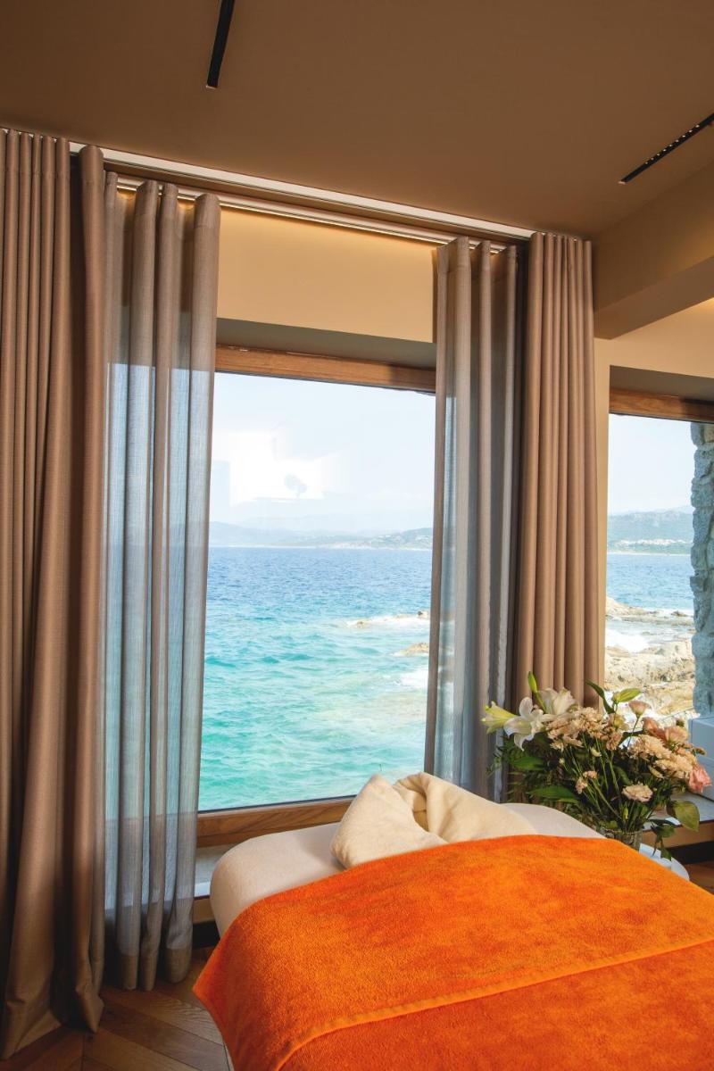 une chambre avec une grande fenêtre donnant sur l'océan dans l'établissement Hotel La Pietra Restaurant & Spa, à LʼÎle-Rousse