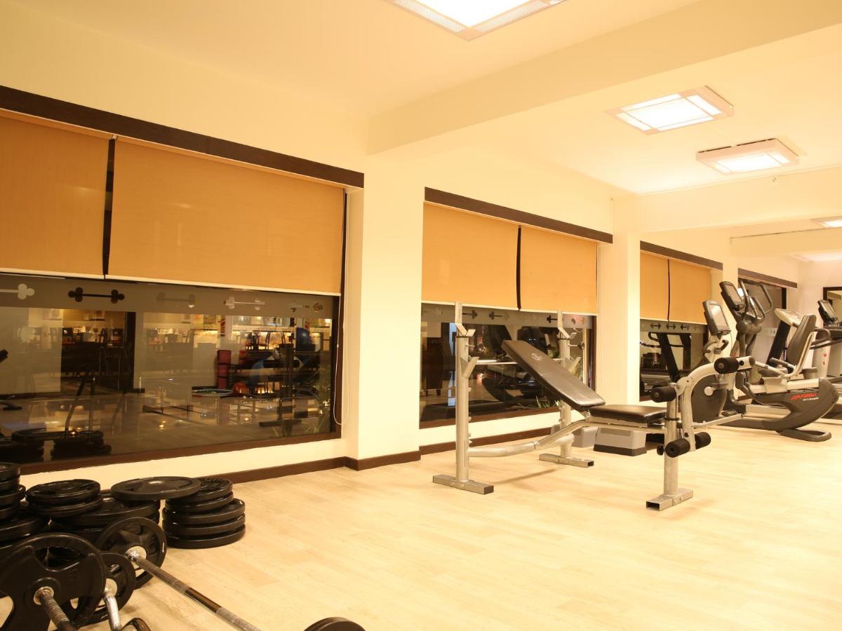 a gym with several chairs and a large window at Deltin Suites in Candolim