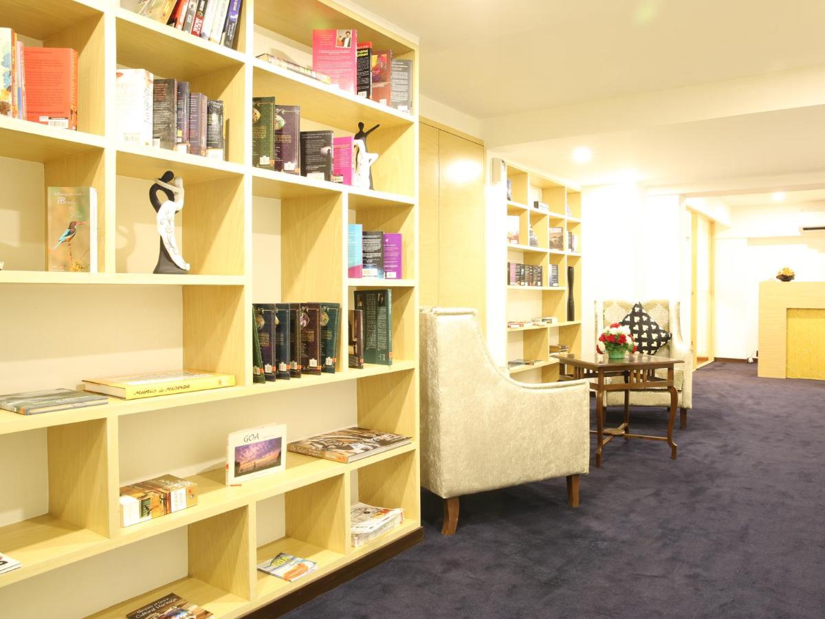 a library with a chair and a desk and bookshelves at Deltin Suites in Candolim