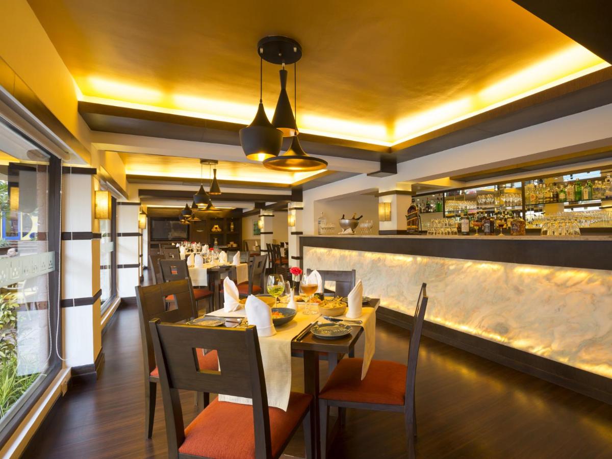a restaurant with a table and chairs and a bar at Deltin Suites in Candolim