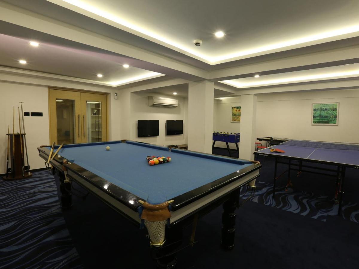 a pool table in a room with two tables at Deltin Suites in Candolim
