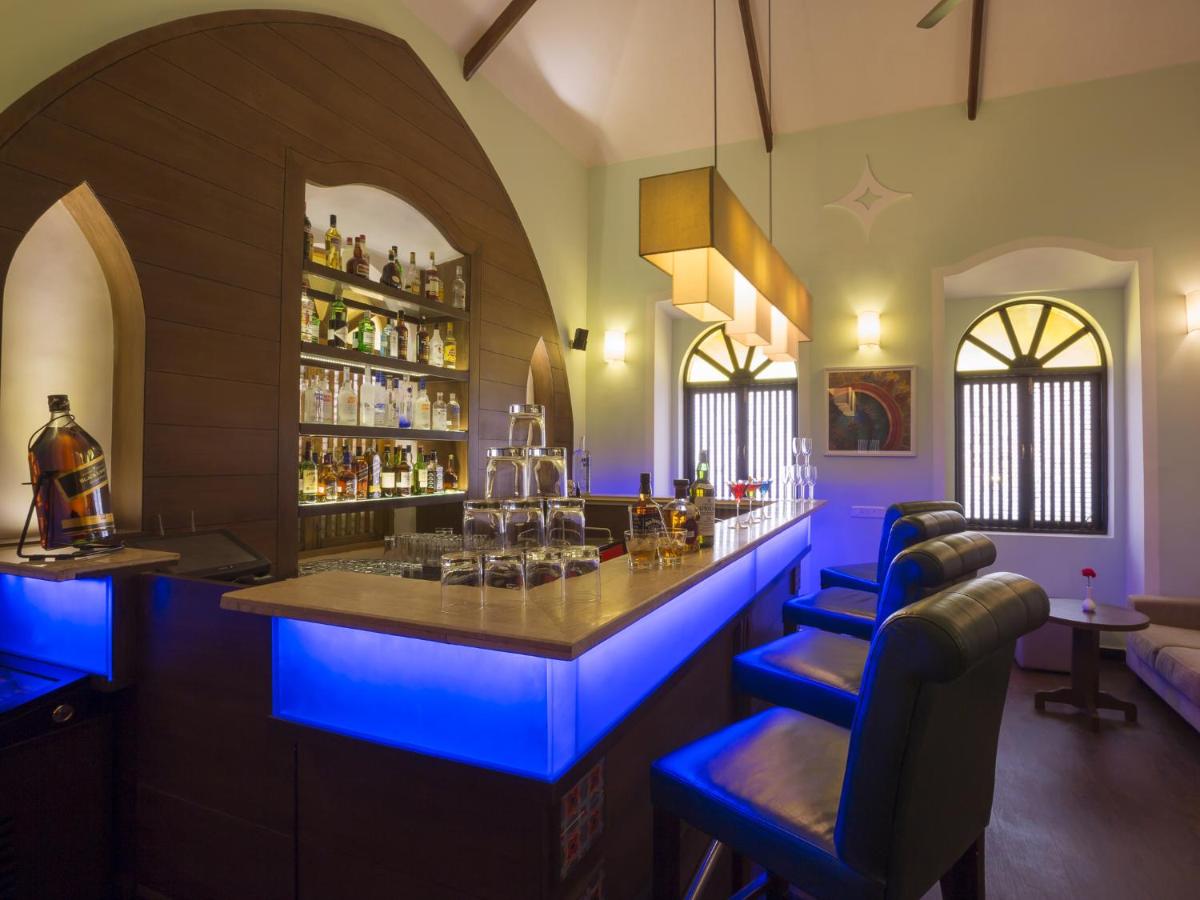 a bar with blue lighting in a room at Deltin Suites in Candolim