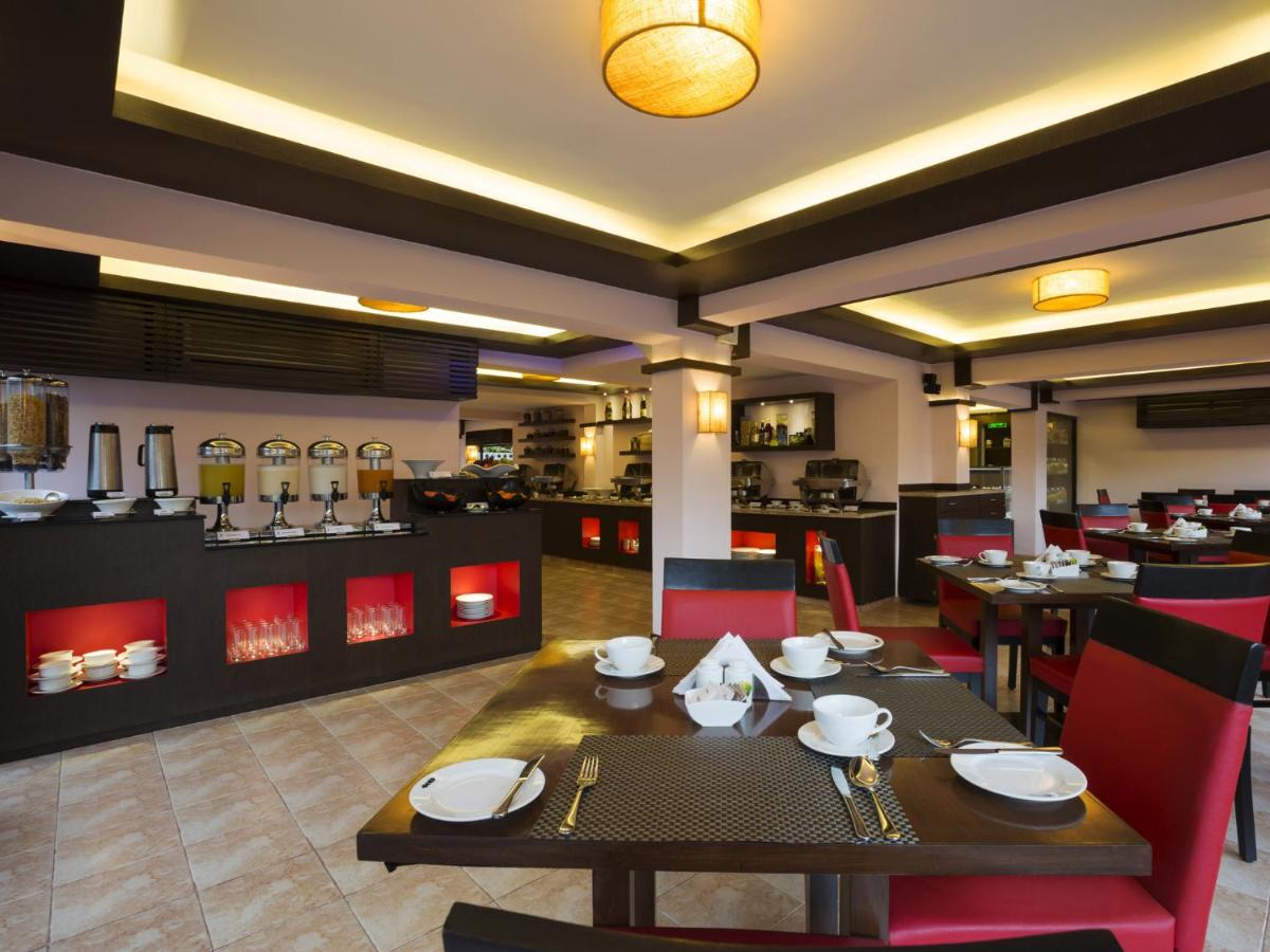 a dining room with a table and chairs and a restaurant at Deltin Suites in Candolim