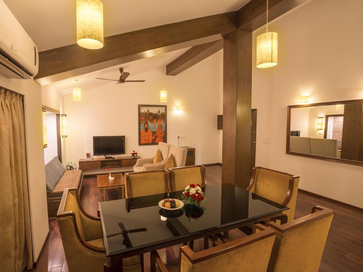a dining room and living room with a table and chairs at Deltin Suites in Candolim