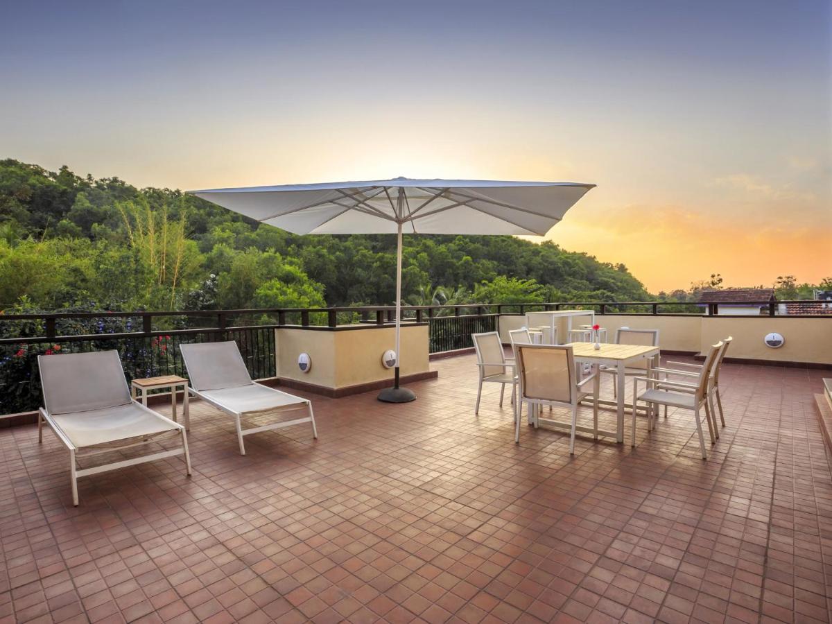 a patio with a table and chairs and an umbrella at Deltin Suites in Candolim