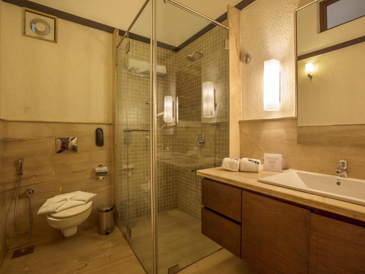 a bathroom with a shower and a toilet and a sink at Deltin Suites in Candolim