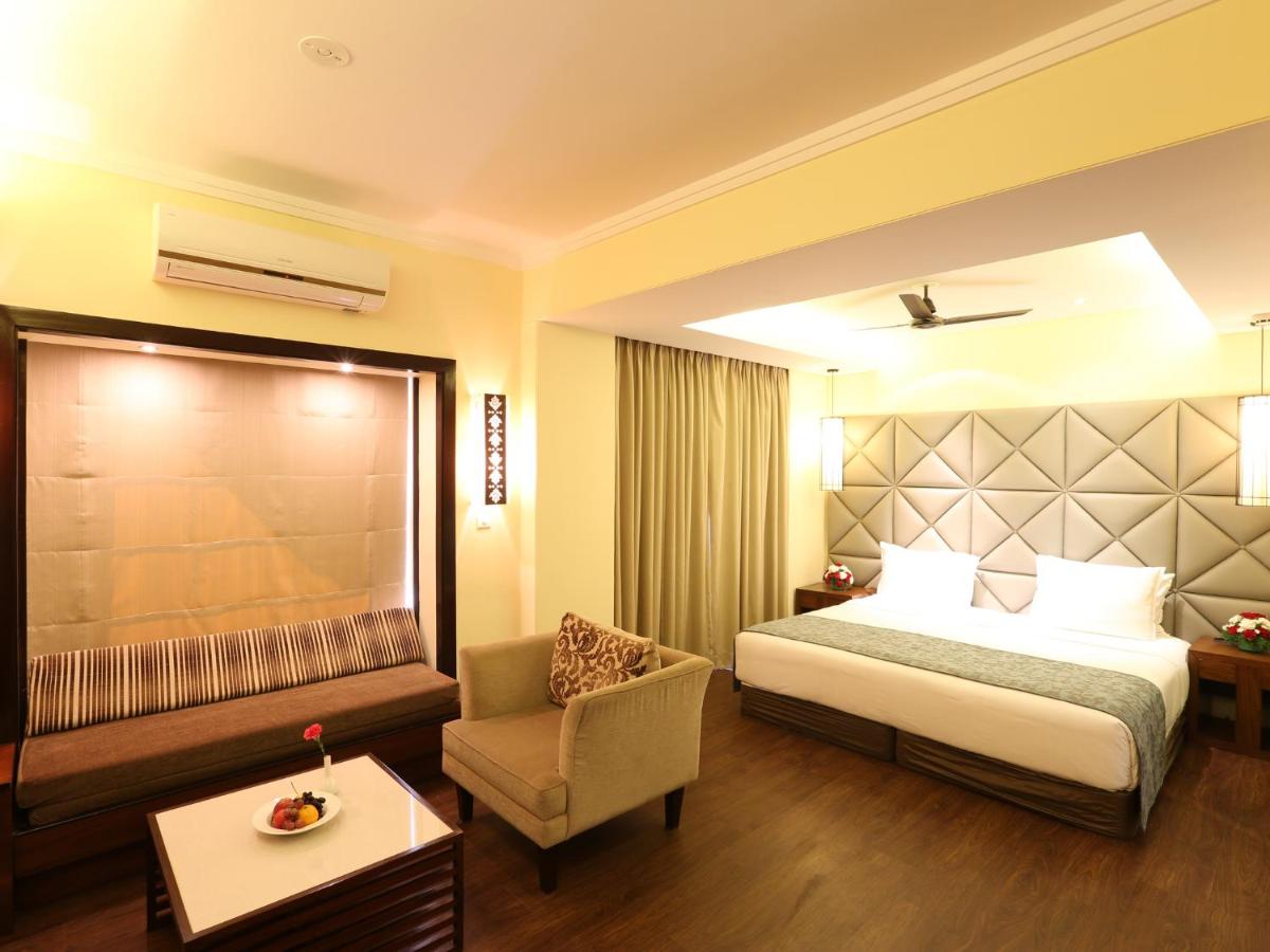 a hotel room with a bed and a chair at Deltin Suites in Candolim