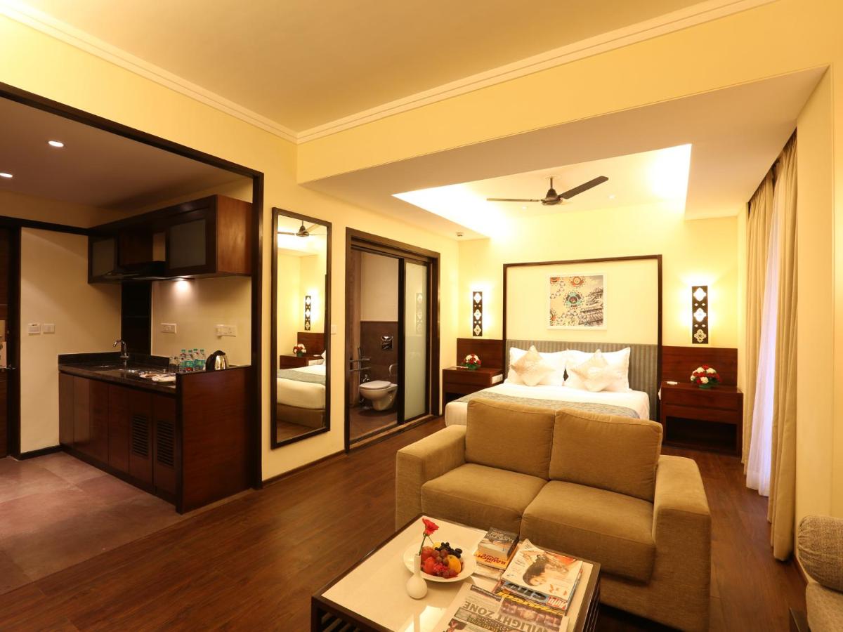a hotel room with a bed and a couch at Deltin Suites in Candolim