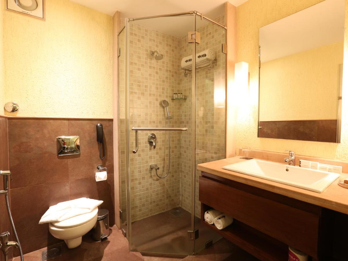 a bathroom with a shower and a sink and a toilet at Deltin Suites in Candolim