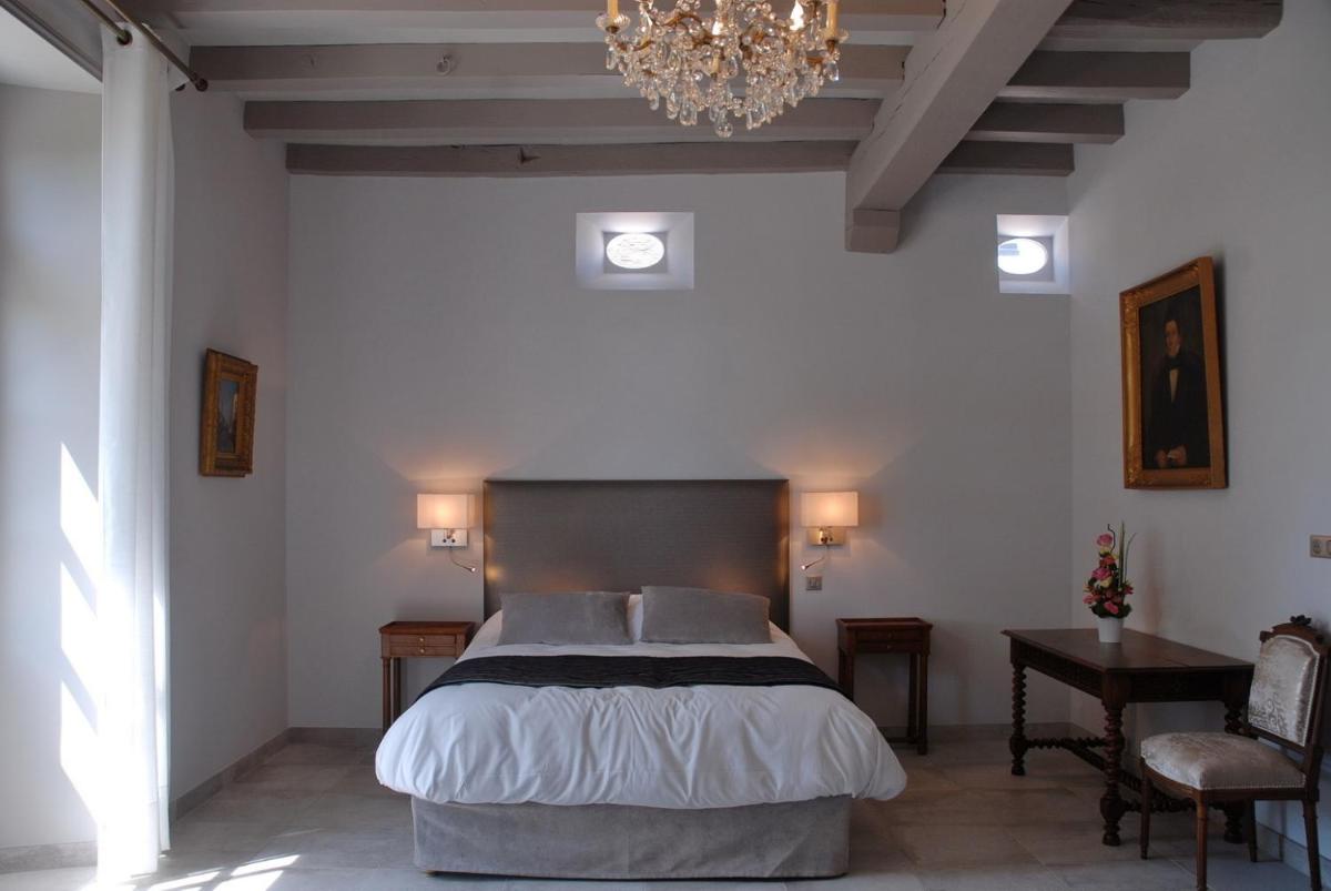 une chambre avec un grand lit et un lustre dans l'établissement Le Logis du Péré, à Saint-Coutant-le-Grand 35 autres photos