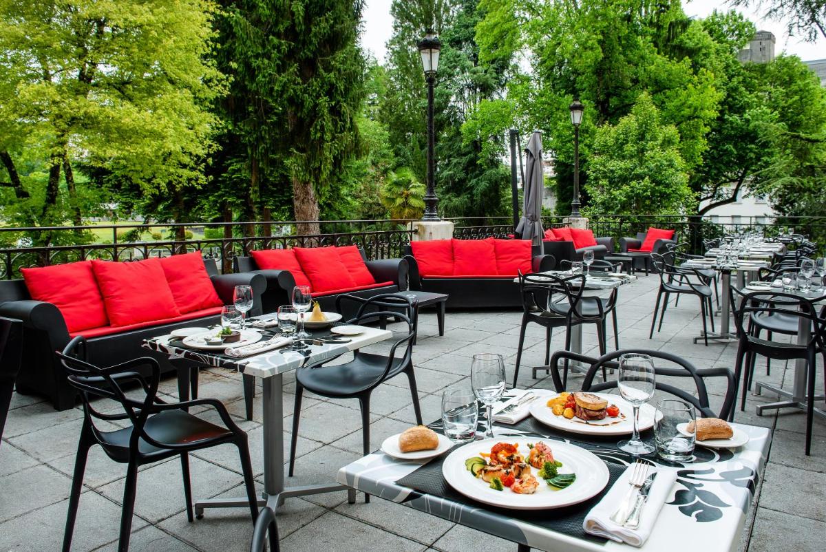 un patio avec des tables et des chaises et des assiettes de nourriture dans l'établissement Grand Hotel Gallia & Londres, à Lourdes 37 autres photos