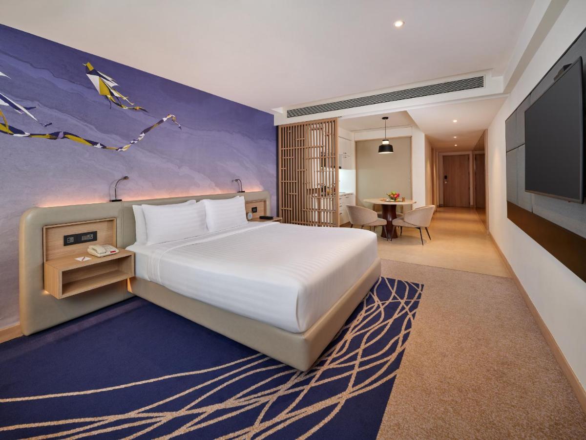 a bedroom with a large white bed and a tv at Novotel Ahmedabad in Ahmedabad