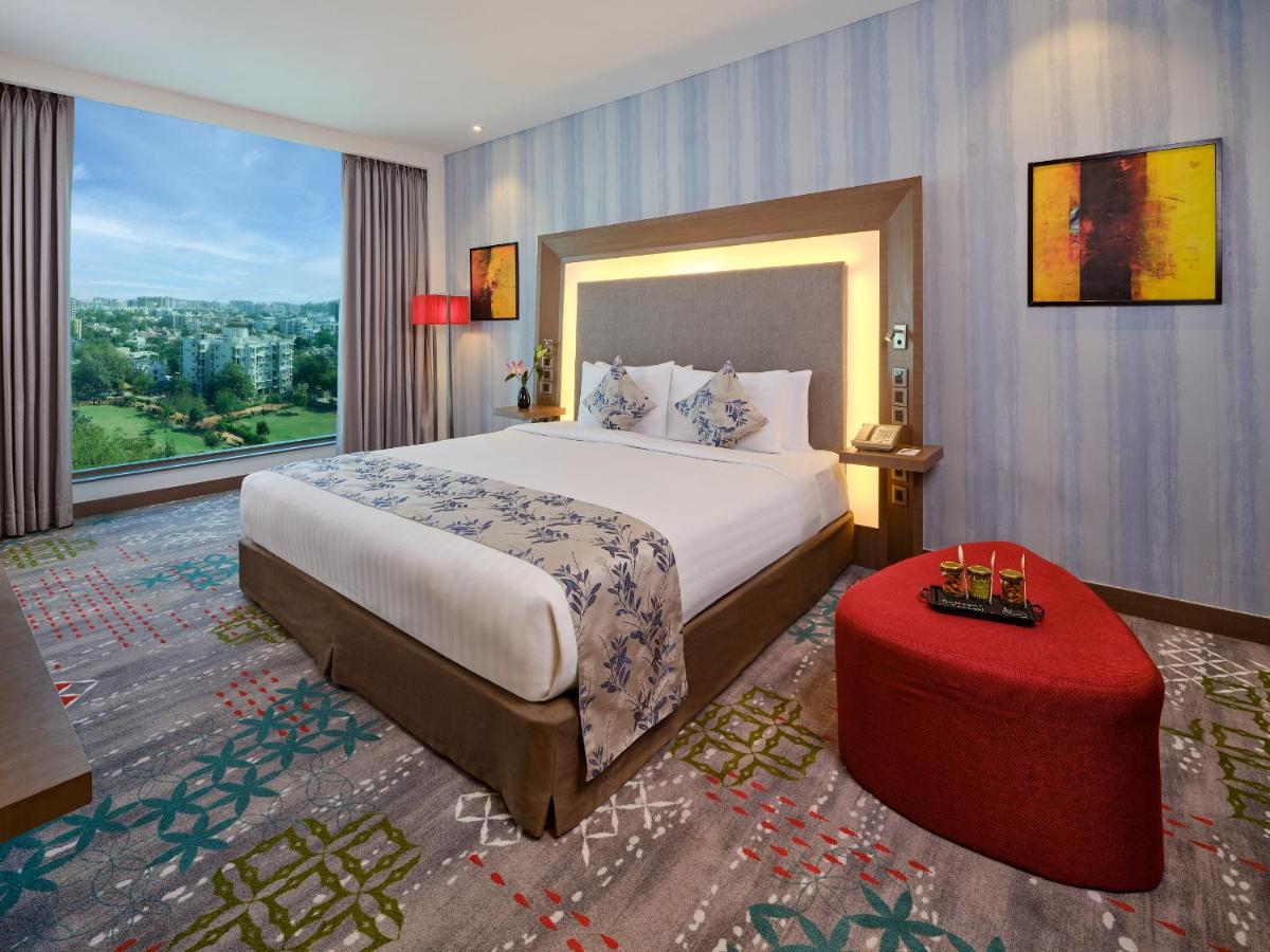 a bedroom with a large bed and a large window at Novotel Ahmedabad in Ahmedabad