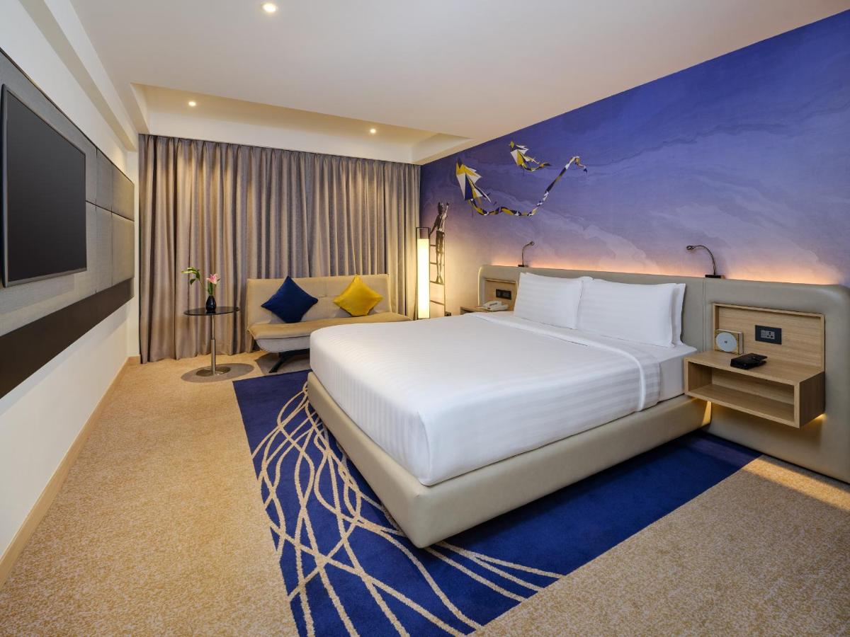 a bedroom with a large white bed and a tv at Novotel Ahmedabad in Ahmedabad