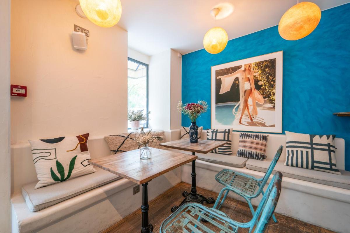 une chambre avec deux tables et des chaises et un mur bleu dans l'établissement La Finca Hôtel & Spa, à Paris