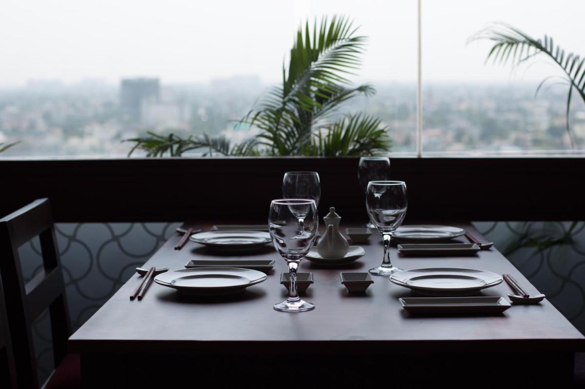 a table with plates and glasses on a table with a window at The Accord Metropolitan in Chennai