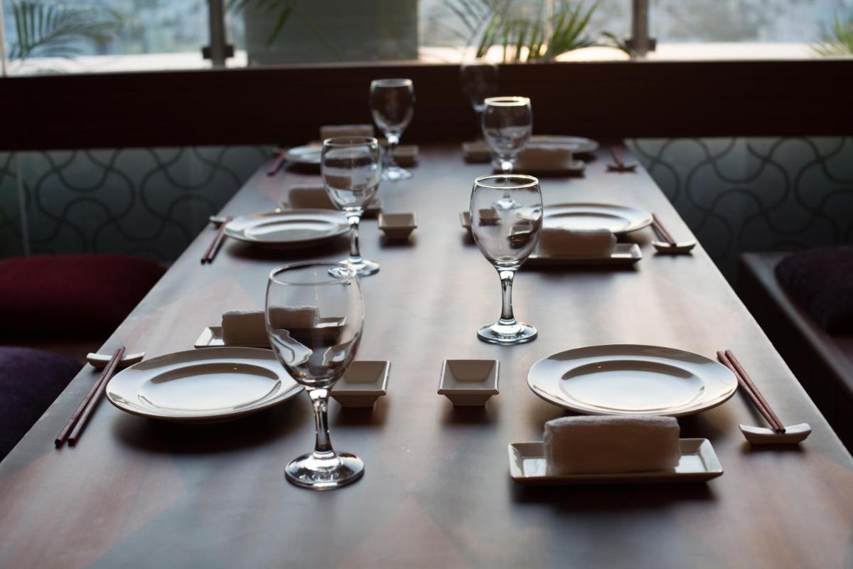 a long wooden table with plates and wine glasses on it at The Accord Metropolitan in Chennai