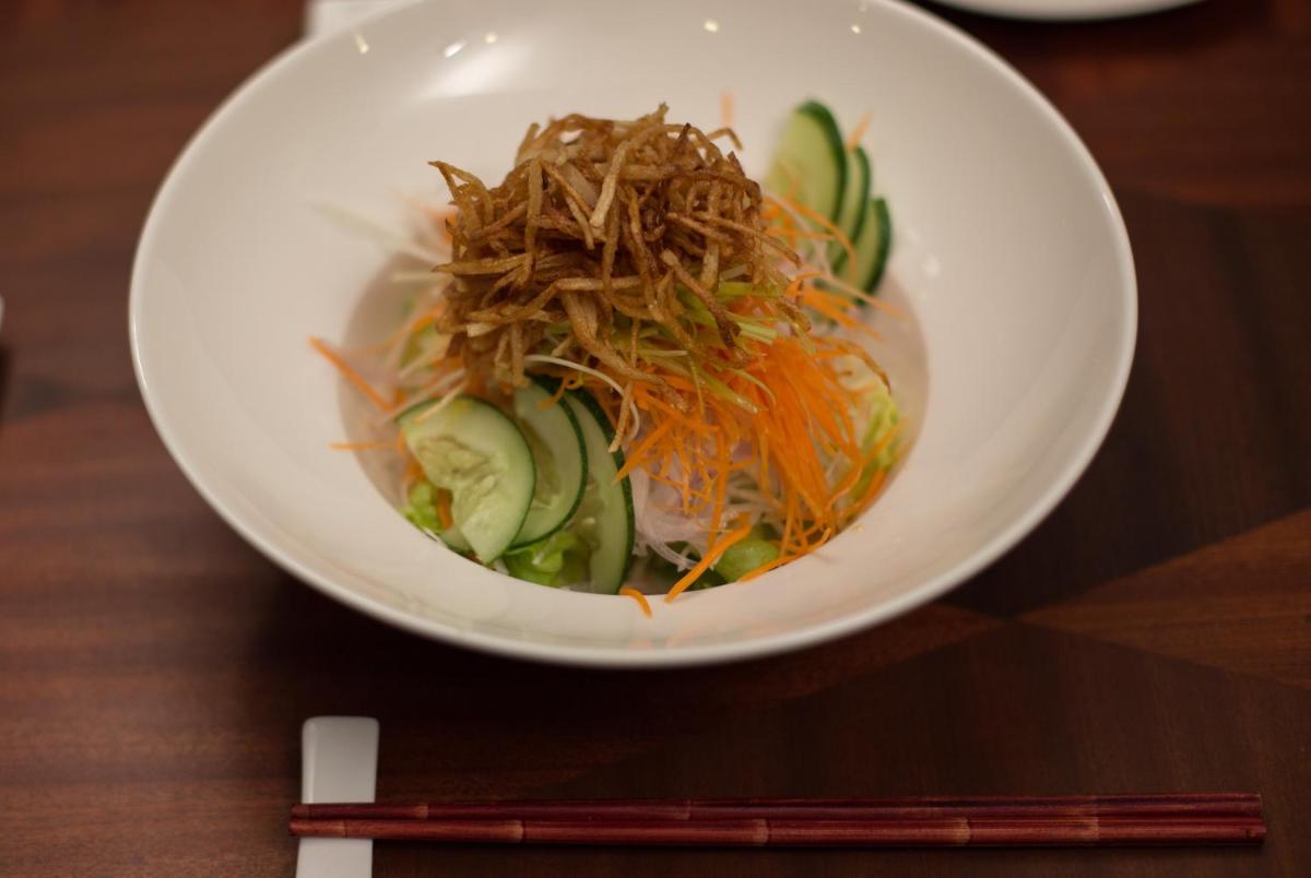 a white bowl of food with carrots and cucumbers at The Accord Metropolitan in Chennai