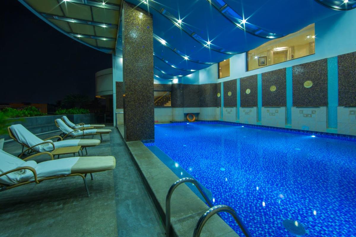 a pool at night with lounge chairs around it at The Accord Metropolitan in Chennai