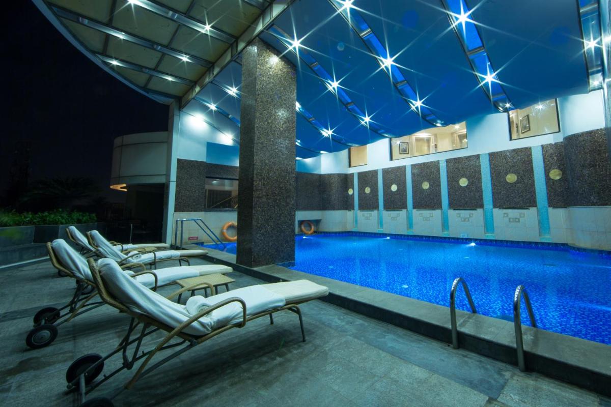 a hotel pool with lounge chairs next to a swimming pool at The Accord Metropolitan in Chennai